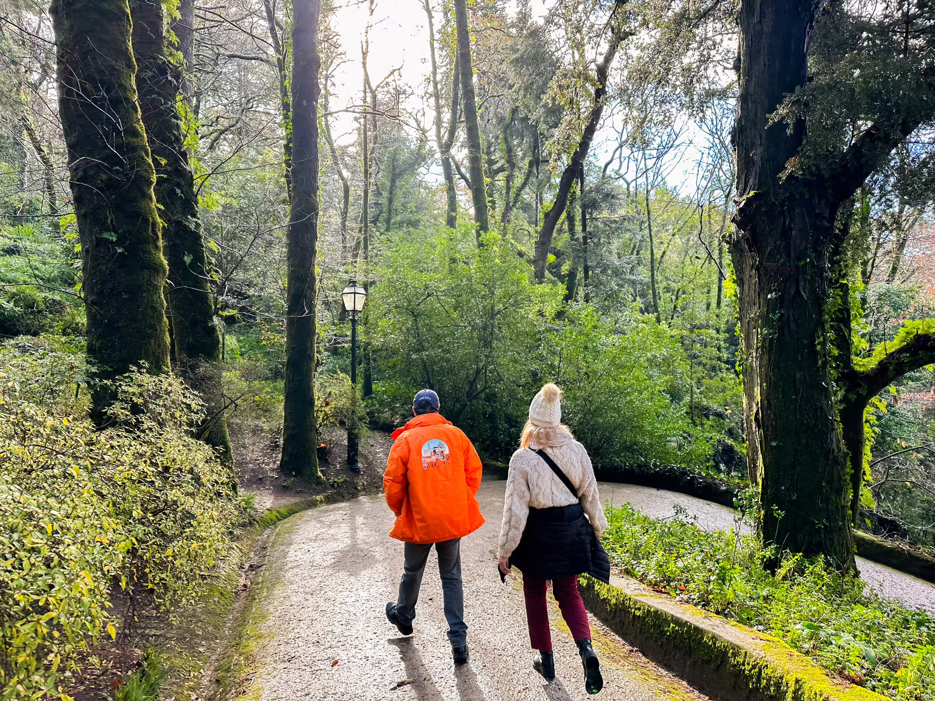 Tourists walking down a scenic forest path in Sintra, highlighting the natural beauty of the private van tour.
