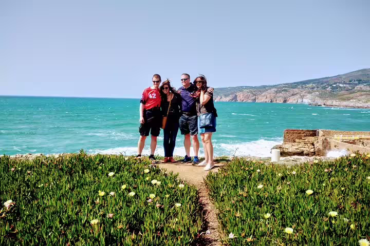 Tourists enjoying the stunning coastal view at Cabo da Roca during the Sintra World Heritage and Cascais Village tour.