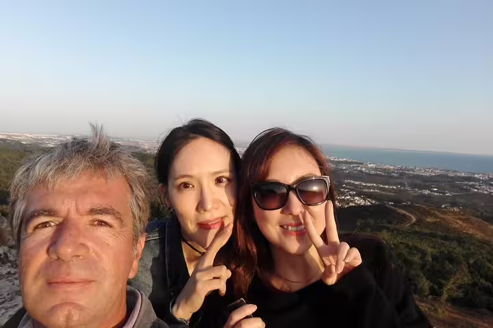 Tourists enjoying a scenic view over Sintra, Cabo da Roca, and Cascais during a full-day private tour, capturing memories.