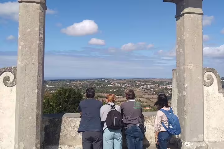 Tourists enjoying panoramic views from a historic lookout point in Sintra, with vast landscapes and blue skies.