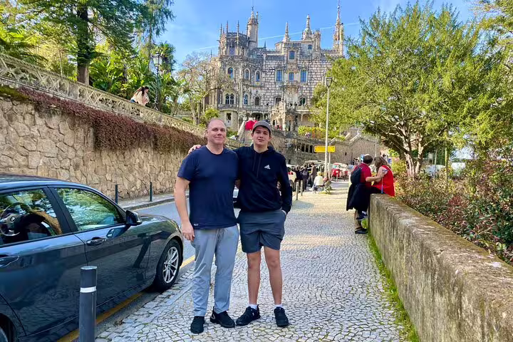 Visitors enjoying a sunny day near the stunning architecture of Sintra during a private tour, featuring hidden gems and wine tasting.