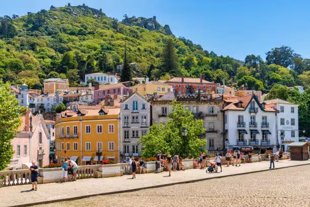 Colorful hillside homes in Sintra, Portugal, with tourists exploring the charming town during a Lisbon day tour.