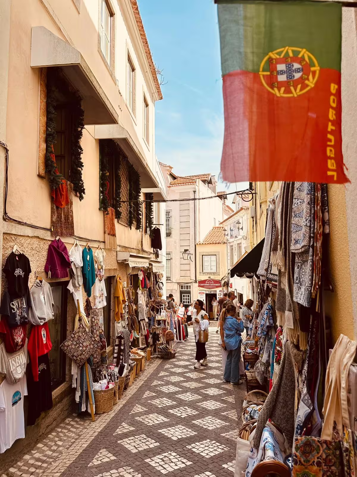 Charming Sintra street lined with colorful shops and Portuguese flag, offering a glimpse of local culture and shopping.