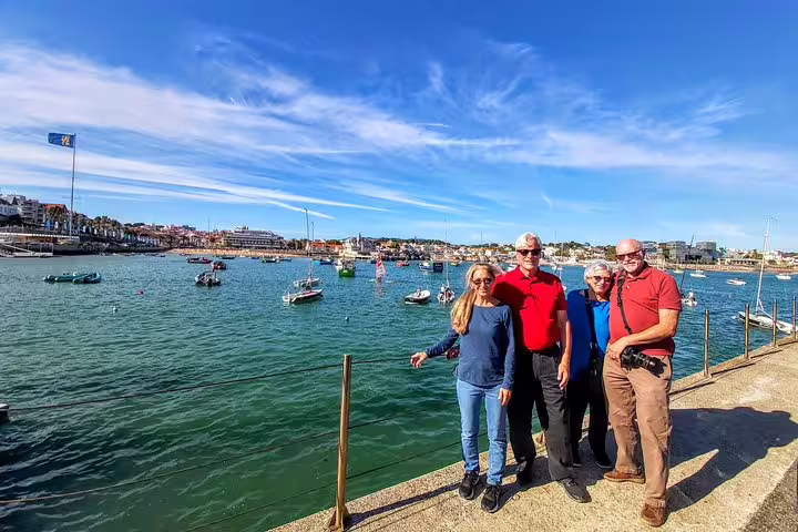 Tourists enjoying a sunny day by the scenic harbor in Cascais, a highlight of the Sintra & Amazing Dream Villages Tour.