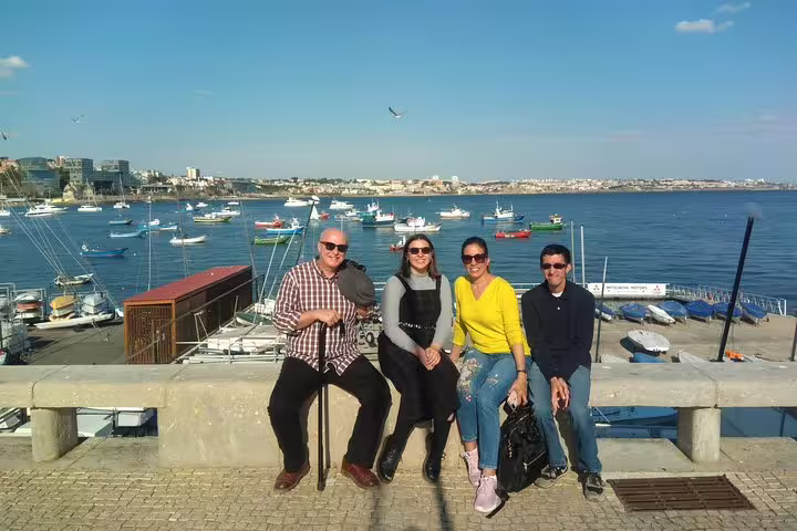 Tourists enjoying the scenic view of a picturesque harbor in Sintra during the Amazing Dream Villages Tour under a clear blue sky.