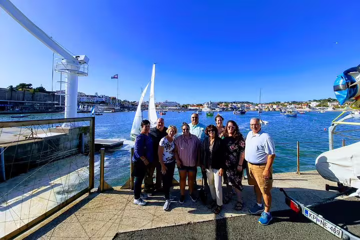A group of tourists enjoying a sunny day by the waterfront in Cascais during the Sintra & The Amazing Dream Villages Tour.