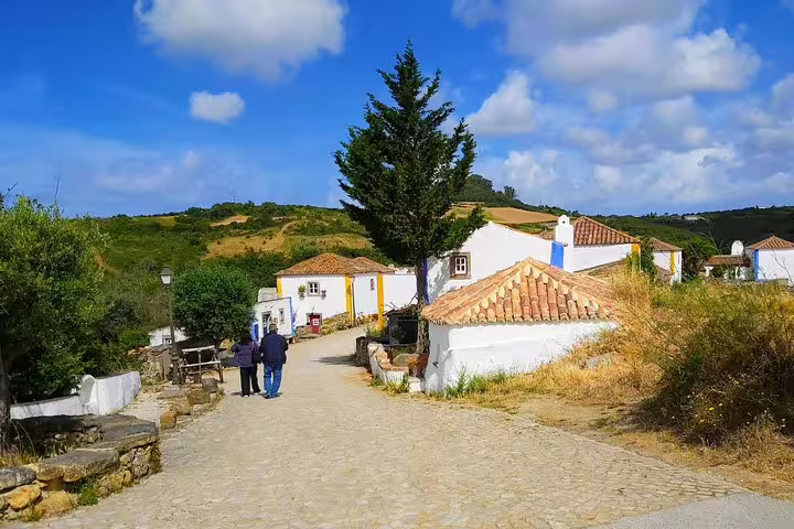Scenic view of a charming village near Sintra with traditional white cottages, cobblestone paths, and lush green landscapes.