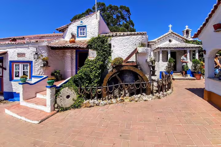 Charming village scene in Sintra showcasing traditional whitewashed houses, vibrant greenery, and historic architecture under a clear blue sky.