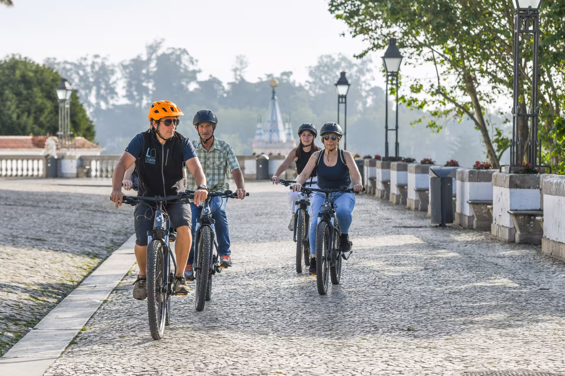 Group of cyclists on Sintra e-bike tour exploring scenic cobblestone paths with historic landmarks.