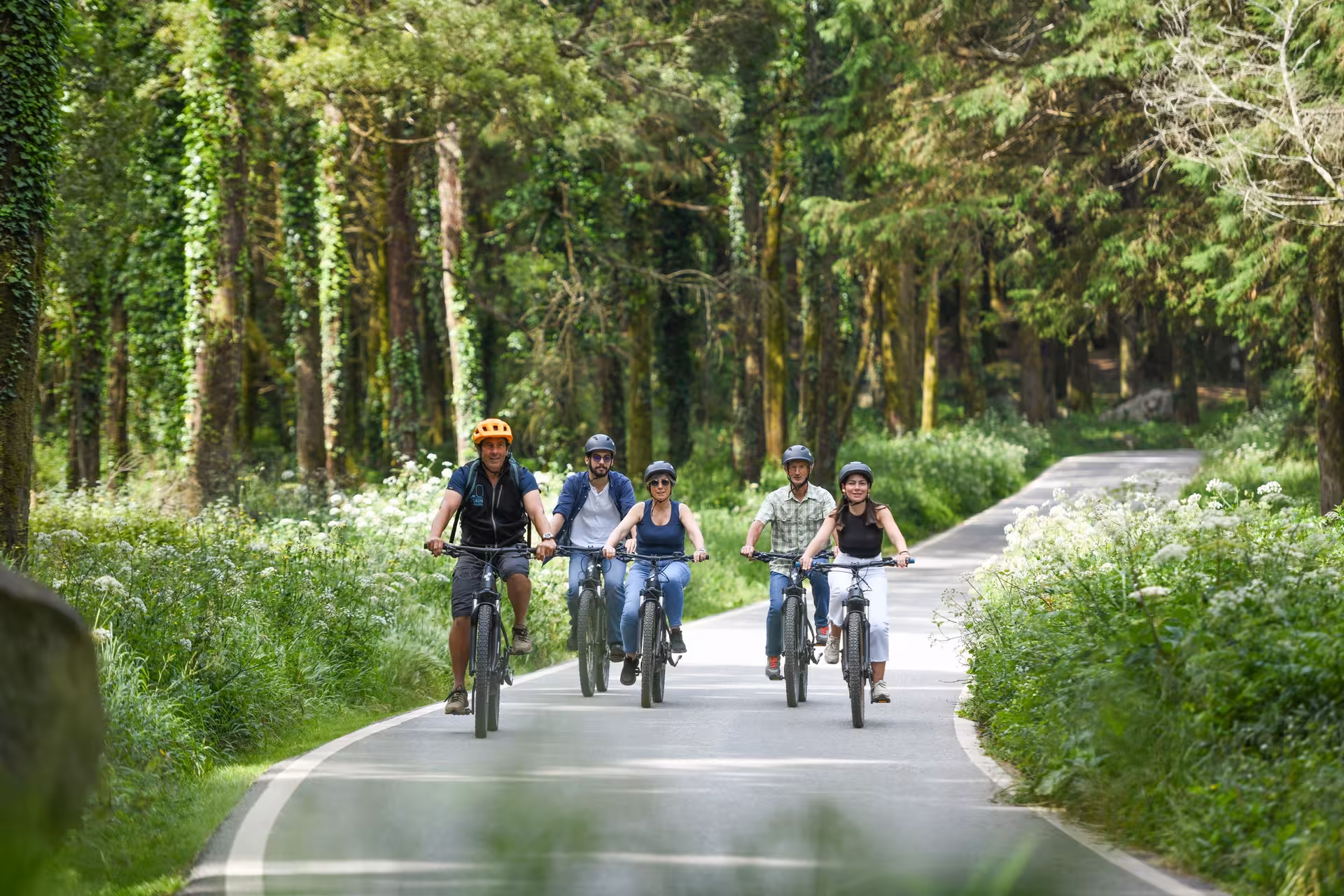 Riders journey through lush green forests on the Sintra 5 Senses e-Bike Tour, surrounded by nature.