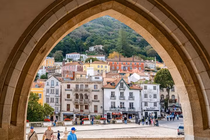 Charming view of Sintra's colorful historic buildings framed by an arch, highlighting the town's architectural beauty.