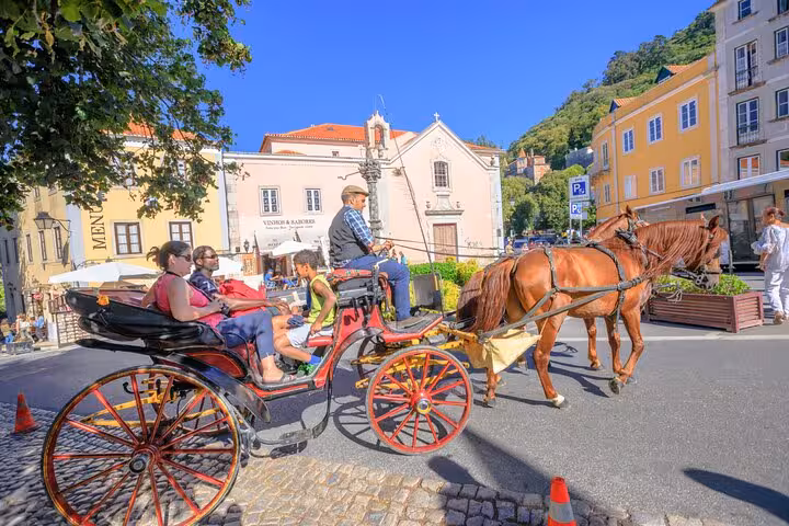 Horse-drawn carriage tour through Sintra's charming streets with colorful buildings in the background.