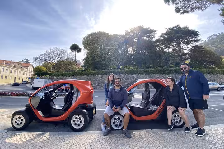 Group posing by red electric cars in Sintra, ideal for self-drive tour to all monuments and palaces