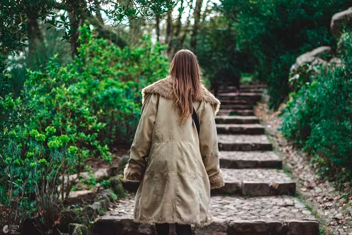 Traveler walking up stone steps in Sintra forest, exploring monuments on a self-drive tour itinerary