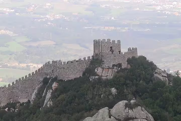 Scenic view of the Moorish Castle in Sintra, surrounded by lush greenery, perfect for a private tour from Lisbon exploring historic palaces.