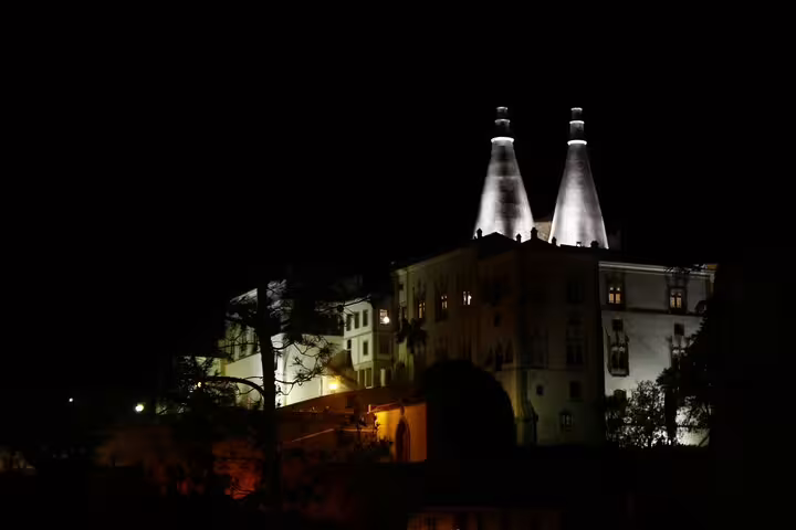 Illuminated at night, the iconic chimneys of Sintra's National Palace stand majestically, highlighting the allure of the Private Tour from Lisbon.