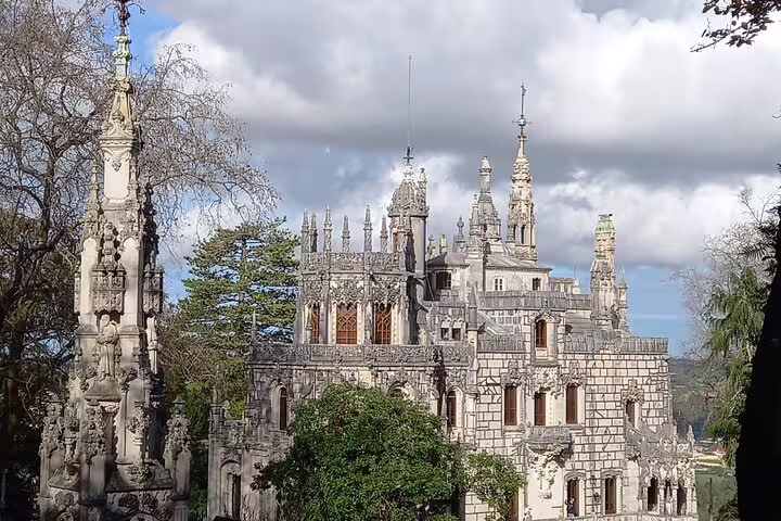 Majestic Gothic palace surrounded by trees under a cloudy sky in Sintra, featured on private tour from Lisbon.