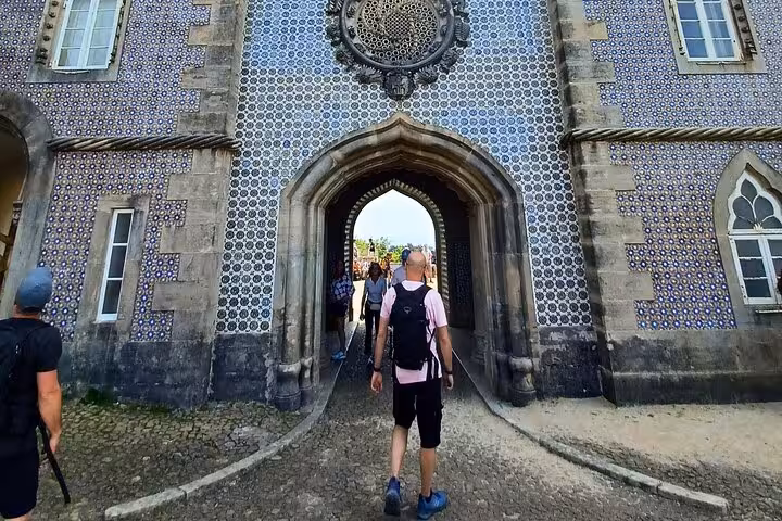Traveler walking through tiled archway at Sintra palace entrance on tuk tuk tour from Sintra to Cascais