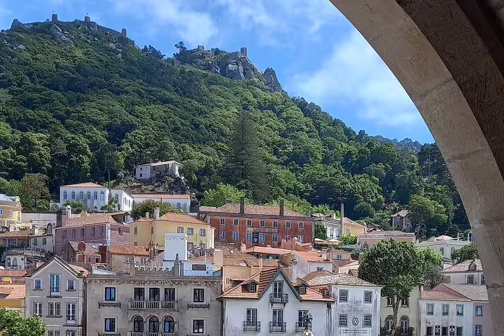Charming hillside view of Sintra, Portugal, with colorful buildings nestled against lush green mountains.