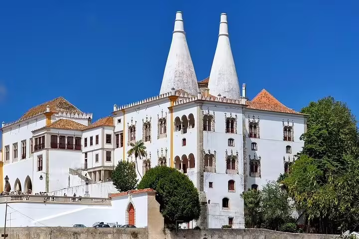 Sintra National Palace under a clear blue sky, showcasing its iconic chimneys, part of the Small-Group Pena Palace & Regaleira Tour.