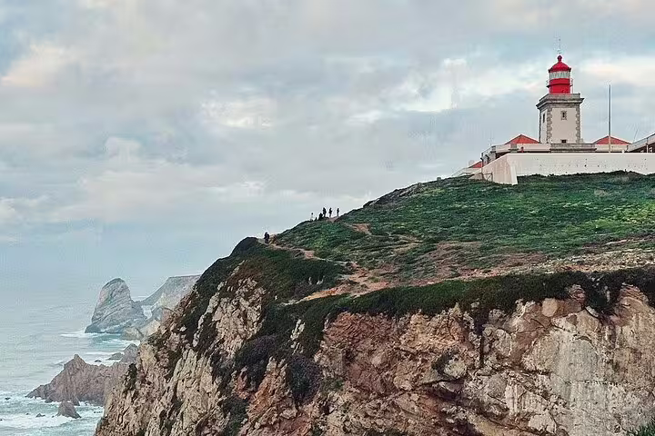 Scenic view of Cabo da Roca lighthouse perched on rugged cliffs with ocean backdrop, part of Sintra's full-day tour experience.