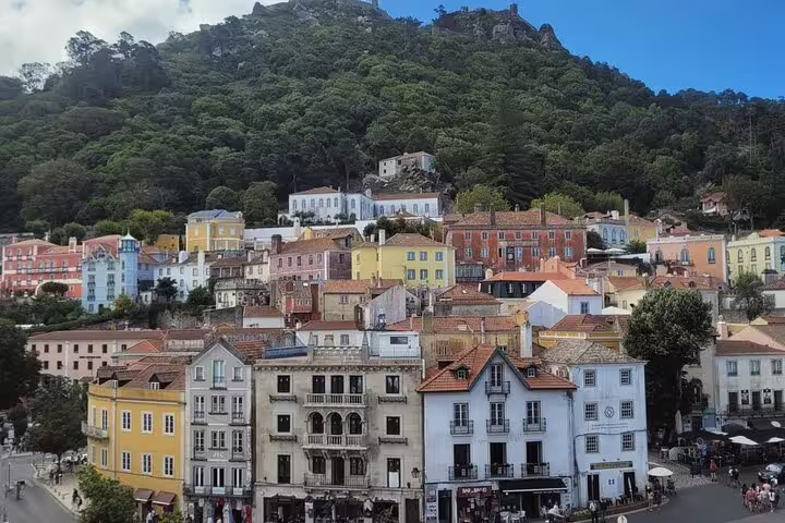 Colorful hillside village with traditional architecture in Sintra, Portugal, surrounded by lush greenery, ideal for tourism.
