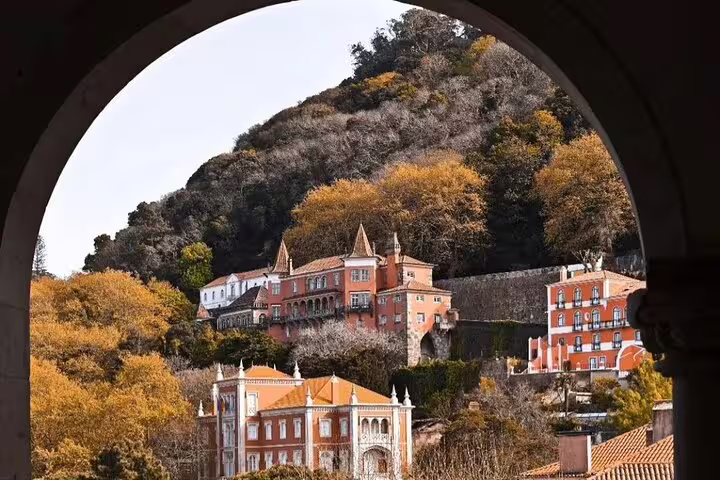Scenic view of colorful historic buildings nestled in the lush, forested hills of Sintra near Pena Palace on a guided tour.