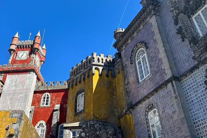 Vibrant view of Sintra's colorful Pena Palace, showcasing its unique architecture on a guided half-day tour with tickets.