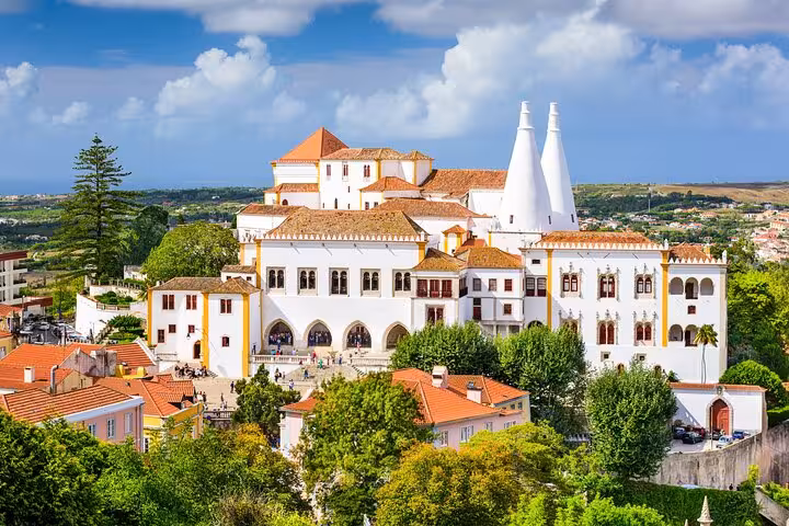 Majestic view of Sintra National Palace with iconic chimneys and lush gardens, featured in the Sintra day tour.