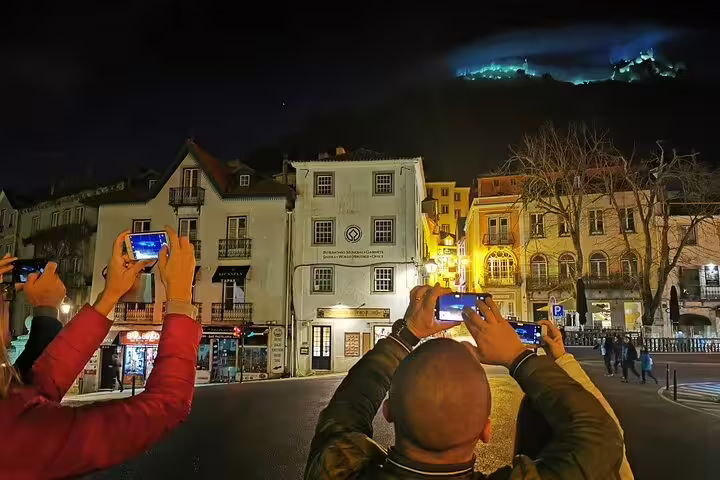 Tourists capturing the illuminated Sintra skyline at night during a private tour with Pena Palace tickets, highlighting local charm.