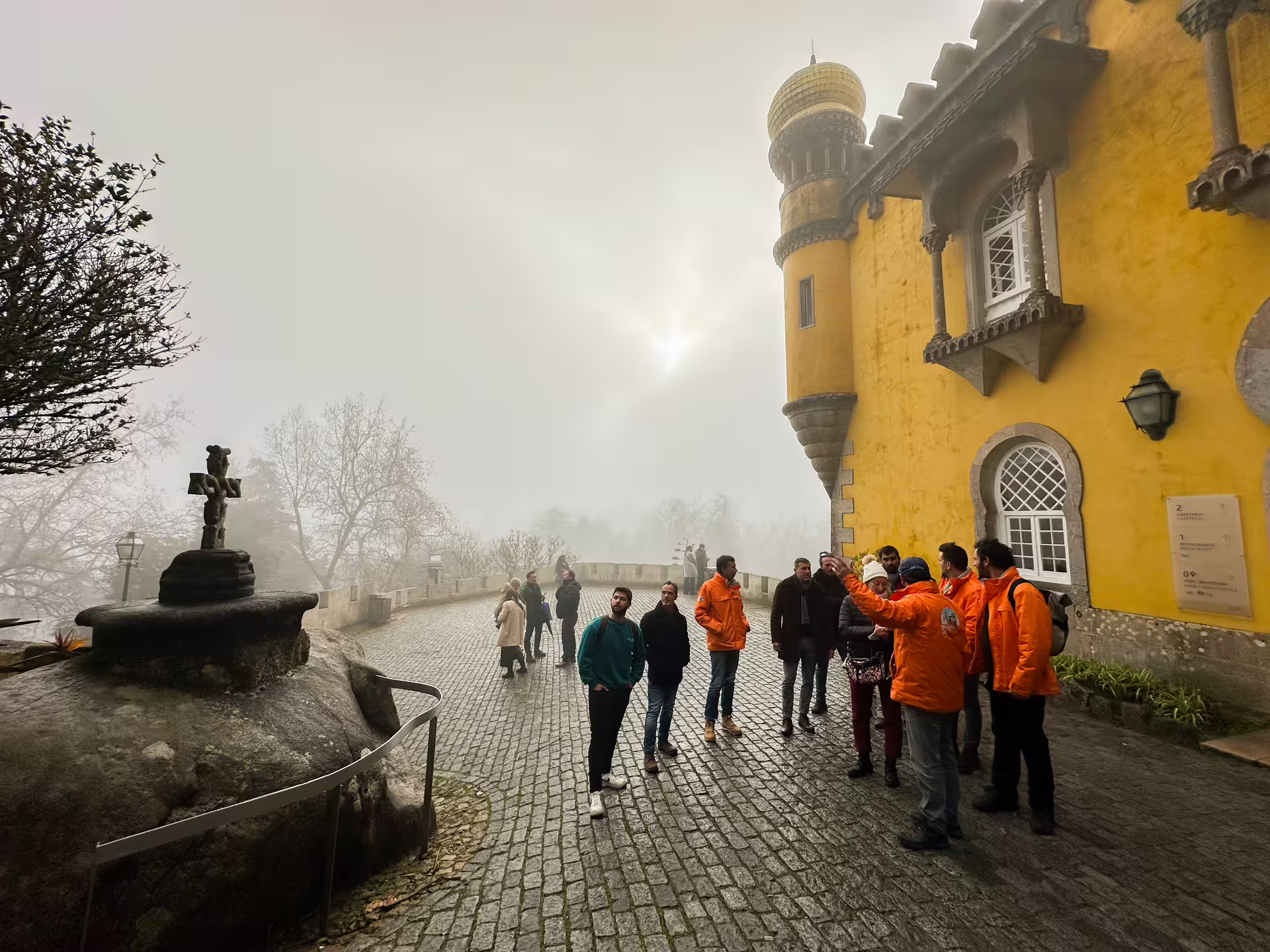 Tour group exploring the misty courtyard of Pena Palace during Sintra private van tour.