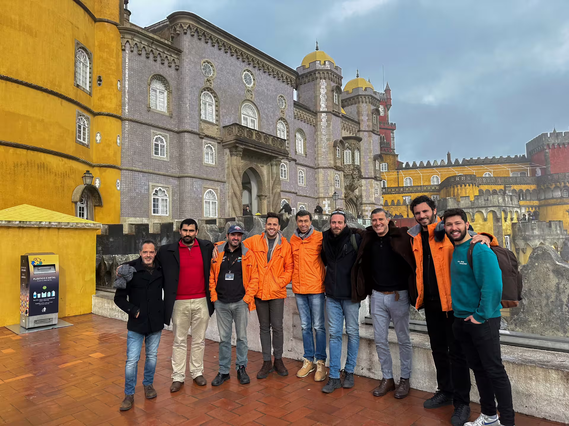 Group of tourists posing in front of the colorful Pena Palace on a Sintra private van tour.