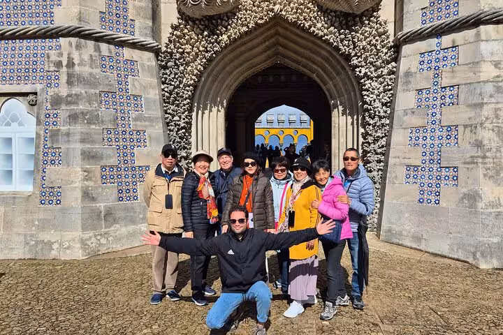 Group of tourists smiling in front of the ornate entrance of Pena Palace during Sintra private day tour.