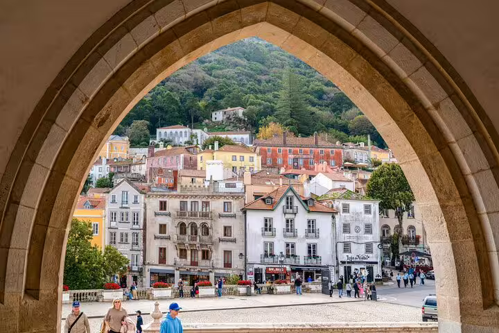 View of charming Sintra village framed by an arch, showcasing colorful architecture and lush hills on a Pena Palace tour.