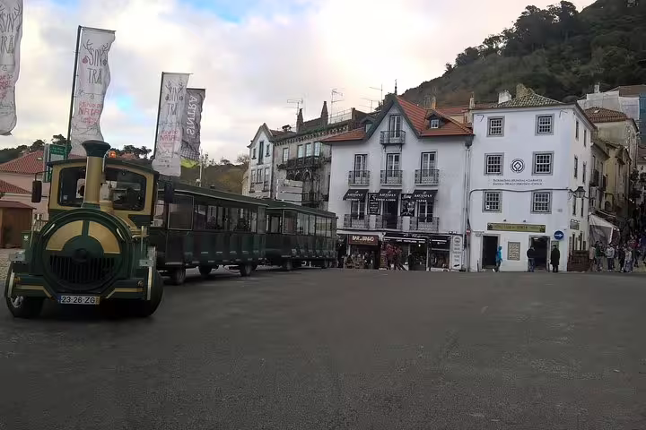 Historic Sintra village square with a charming tourist tram, featuring scenic views from the Pena Palace and Cascais tour.