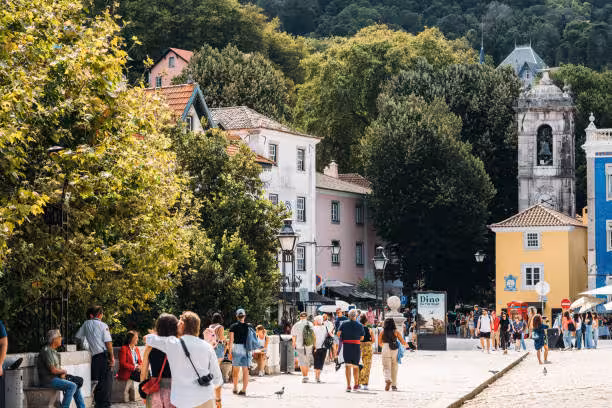 Charming street scene in Sintra, Portugal, with tourists exploring picturesque historic buildings and lush greenery.