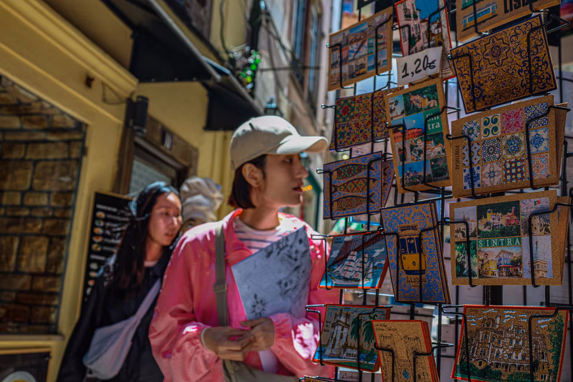 Visitors browse colorful Sintra-themed postcards in a quaint street shop, highlighting local charm and souvenirs.