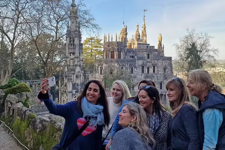 A group of tourists takes a selfie in front of the stunning architecture of Quinta da Regaleira during a Sintra private tour.