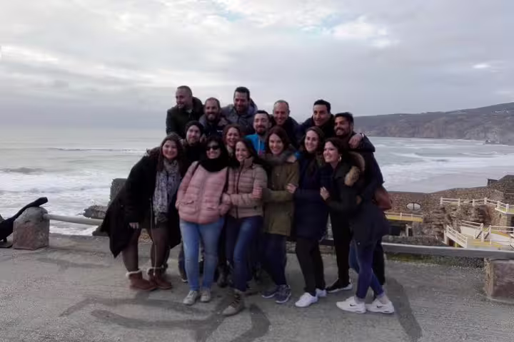 A joyful group enjoys stunning ocean views on a Sintra, Roca, and Cascais full-day private tour with Pena Palace tickets.