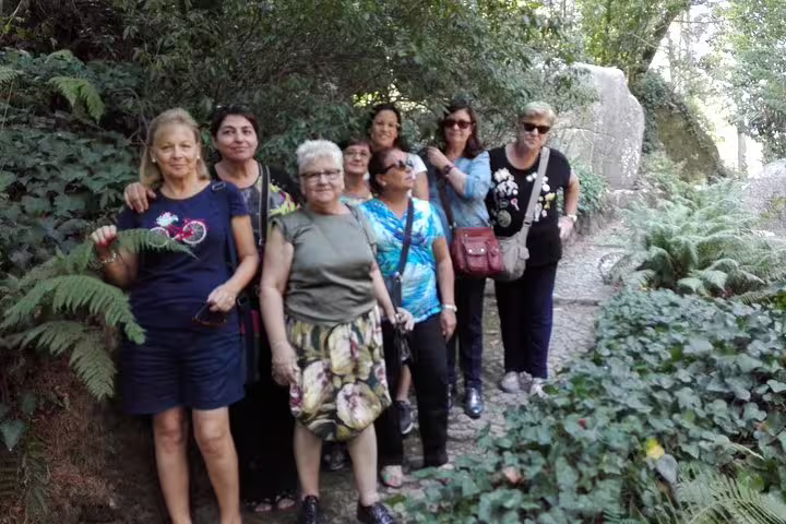 A group of tourists enjoying a scenic walk through lush greenery on the Sintra, Roca, and Cascais full-day private tour.