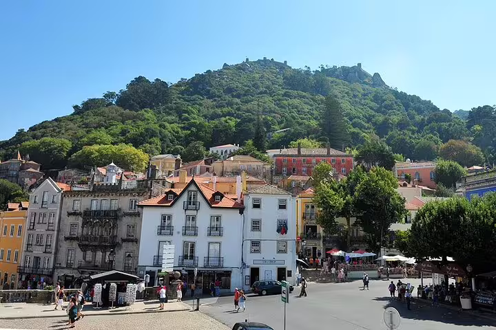Charming Sintra town square with colorful buildings against a lush green hillside, perfect for guided tours in Lisbon.