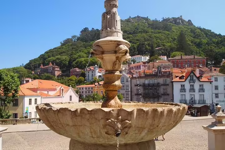 Fountain in picturesque Sintra town square with colorful historic buildings, perfect for a Pena Palace and Regaleira tour.