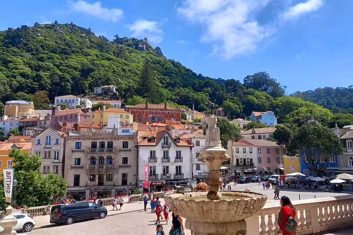 Vibrant town square in Sintra, Portugal, featuring a historic fountain and picturesque architecture under a blue sky.