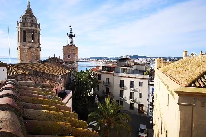 Scenic view of Sitges with historic church tower and Mediterranean Sea, highlighting its coastal charm.