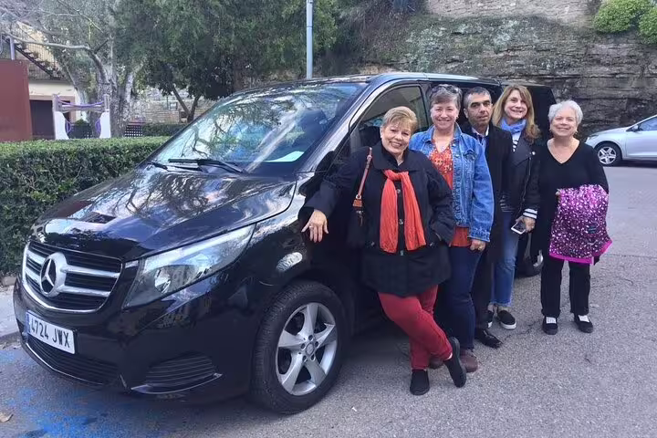 Group of tourists posing by a black Mercedes van on a Wine Celler Penedés and Sitges tour, ready for adventure.