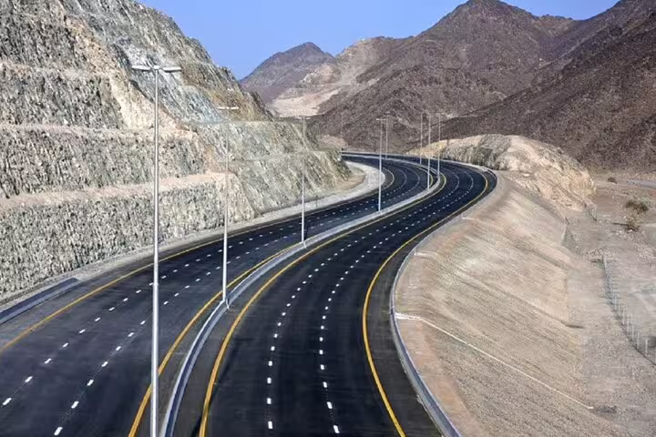 Modern highway nestled between rugged mountains, part of the Six Emirates Tour in a 4x4 from Dubai.
