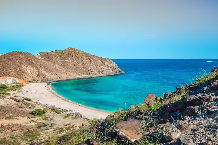 Relax on a pristine, secluded beach with clear blue waters on a Six Emirates Tour in a private 4x4 from Dubai.