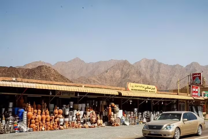Traditional pottery market against the backdrop of the Hajar Mountains on the Six Emirates tour from Dubai.