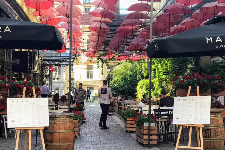 Skadarlija bohemian quarter cafe lane with red umbrellas in Belgrade, featured on Your Own Belgrade walking tour