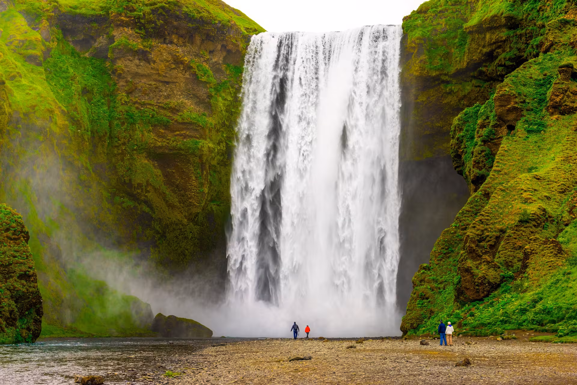 Majestic Skógafoss waterfall cascading down lush green cliffs, a highlight of Iceland's South Coast tour.